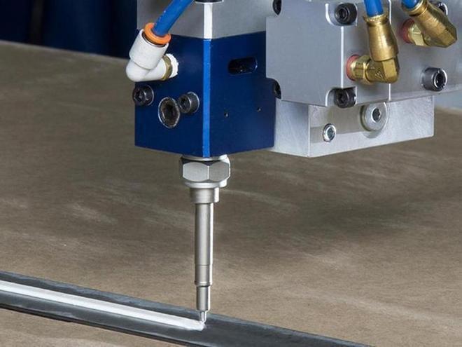 Eine automatische Beschichtungsanlage von Nordson Industrial Coating Solutions (Dosierventil) trägt eine Weiße Klebstoff. auf.